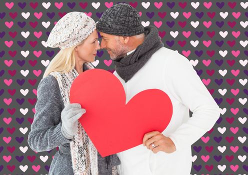 Smiling couple in winter fashion posing with heart shape against valentines day pattern