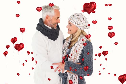Happy couple in winter fashion embracing against red heart balloons floating