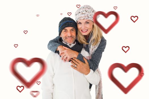 Happy couple in winter fashion embracing against hearts