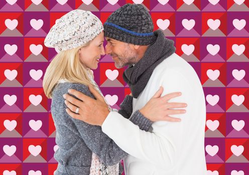 Happy couple in winter fashion embracing against valentines day pattern