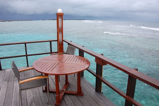 Table and chair at open air cafe with ocean view, Maldives