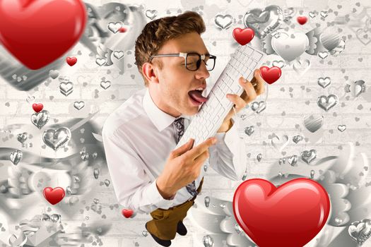 Geeky businessman licking his keyboard against grey valentines heart pattern