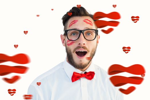 Geeky hipster with kisses on his face against hearts
