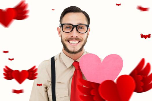 Geeky hipster smiling and holding heart card against hearts