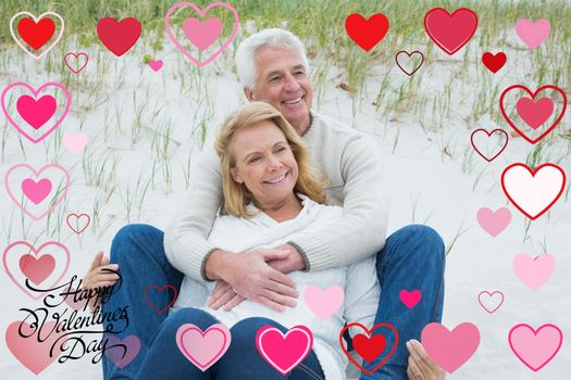 Romantic senior couple relaxing at beach against happy valentines day