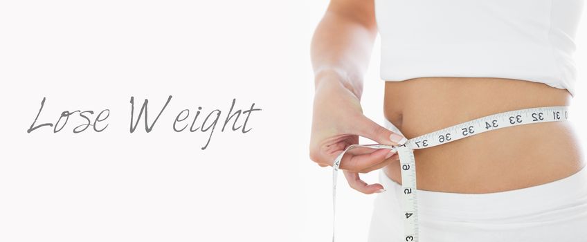 Closeup midsection of woman measuring waist over white background