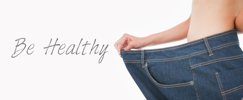 Close up of a woman belly in too big pants against white background