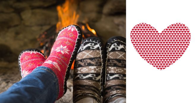 Close up of romantic legs in socks in front of fireplace against valentines day pattern