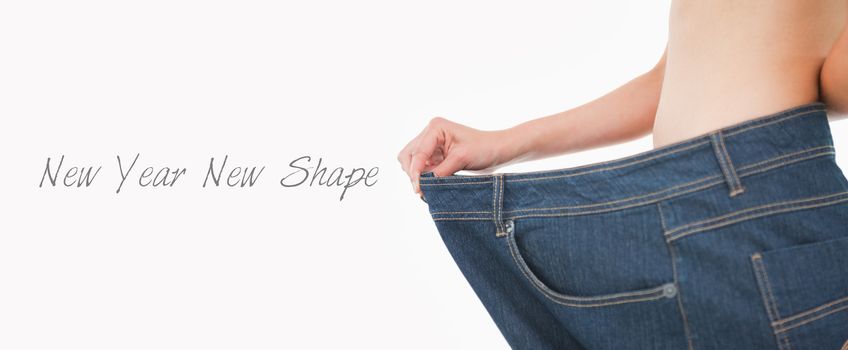 Close up of a woman belly in too big pants against white background