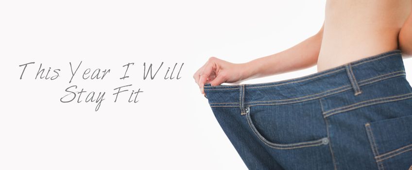 Close up of a woman belly in too big pants against white background