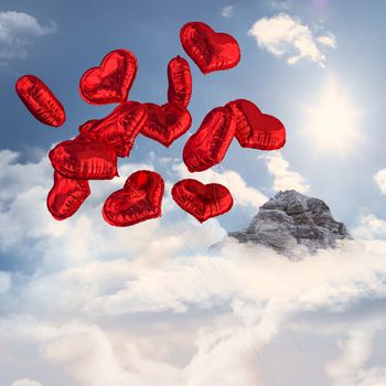 Heart balloons against mountain peak through the clouds