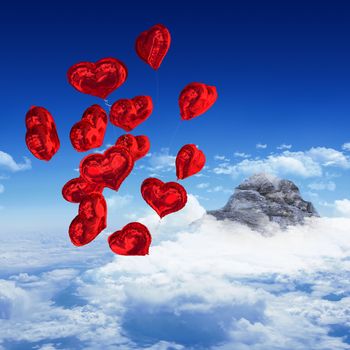 Heart balloons against mountain peak through clouds