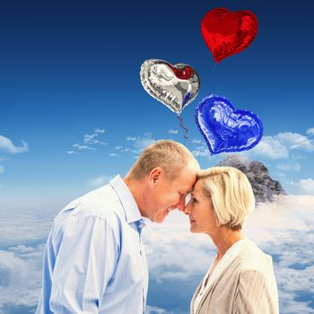 Happy mature couple facing each other against mountain peak through clouds