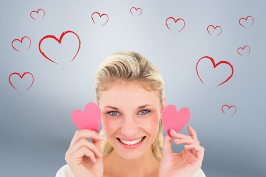 Attractive young blonde holding little hearts  against grey vignette