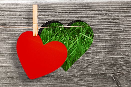 Heart hanging on line against heart in wood