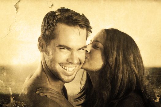 Attractive woman kissing her boyfriend on the cheek against grey background