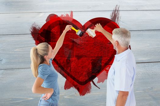 Happy couple painting wall with paintbrushes against grey brick wall