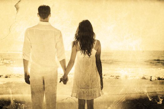 Attractive couple holding hands and watching the ocean against grey background