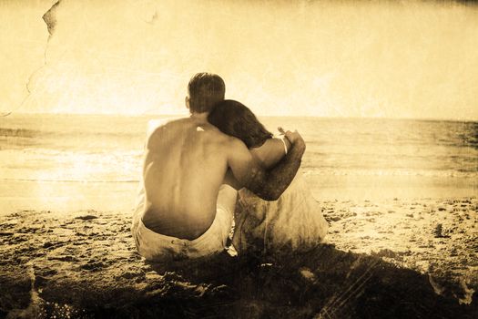 Couple sitting on the sand watching the sea against grey background