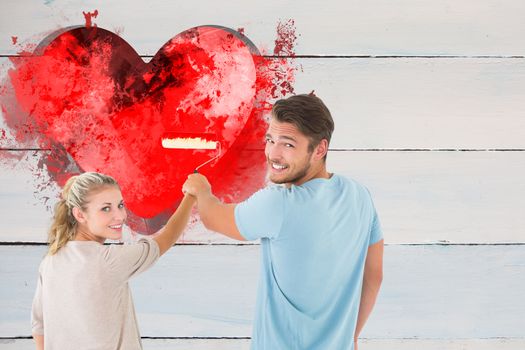 Young couple painting with roller against grey