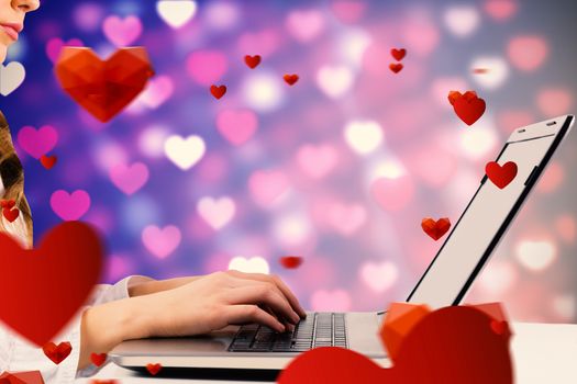 Woman typing on her laptop against valentines heart pattern