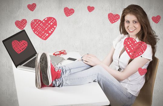 Pretty redhead with feet up on desk against white and grey background