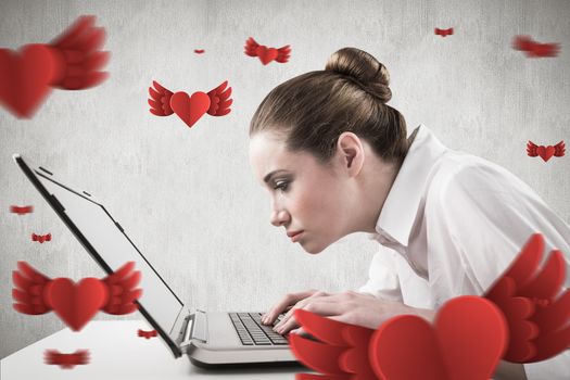 Attentive businesswoman typing on laptop against white and grey background