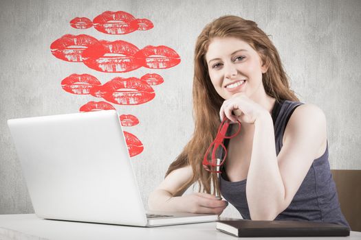 Pretty redhead working on laptop against white and grey background