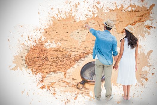 Happy hipster couple holding hands and looking against world map with compass showing north america