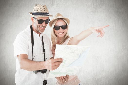 Happy tourist couple using map and pointing against white background