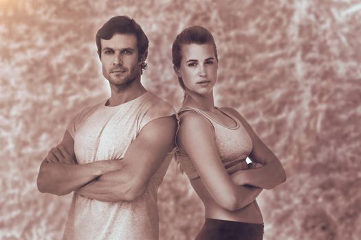 Portrait of a sporty couple with arms crossed against brown