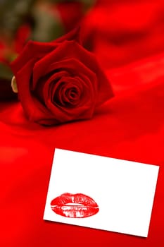 Red rose resting on red silk against white card