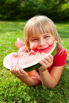 Cute little girl eating watermelon in a garden