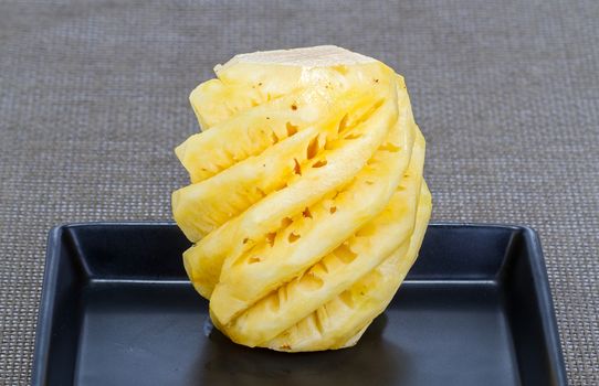 peeled pineapple on black dish