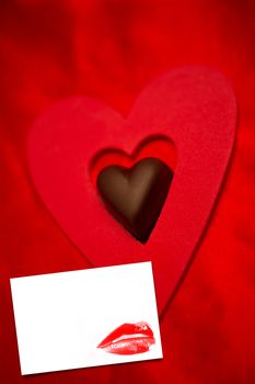 Chocolate love heart and red paper heart  against white card