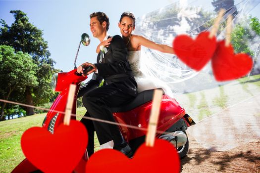 Newlywed couple enjoying scooter ride against hearts hanging on a line