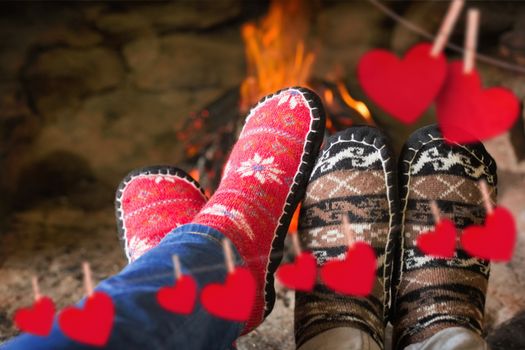 Close up of romantic legs in socks in front of fireplace against hearts hanging on a line