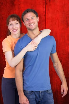 Happy couple looking at camera against red wooden planks