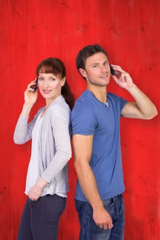 Couple both making phone calls against red wooden planks
