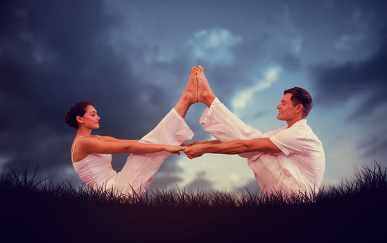 Peaceful couple sitting in boat position together against blue sky over grass