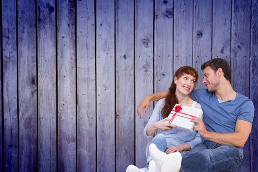 Couple sitting on floor together against wooden planks background