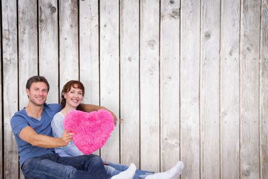 Couple holding a large heart against wooden planks