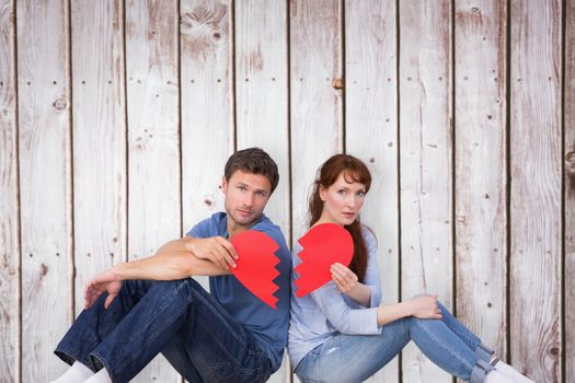 Couple holding a broken heart against wooden planks