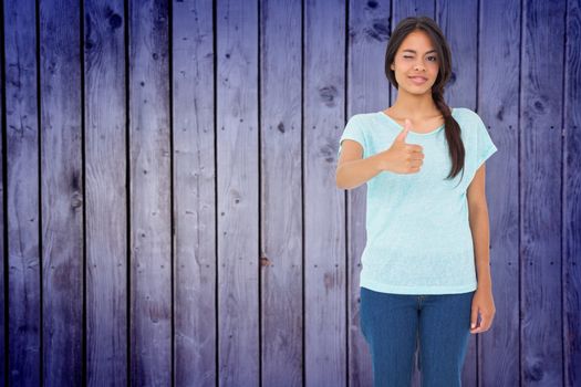 Happy brunette giving thumbs up against wooden planks background
