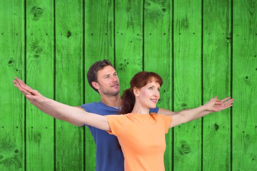 Happy couple looking upwards against bright green wooden planks