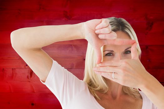 Happy blonde framing with her hands against wooden planks background