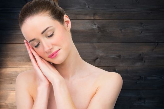 Beautiful brunette with hands at face against wooden planks background