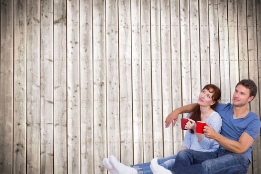 Couple having tea on floor against wooden planks background