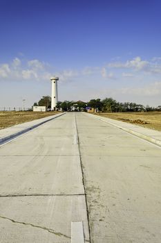 Newly built concrete road leading to a lighthouse undergoing restoration