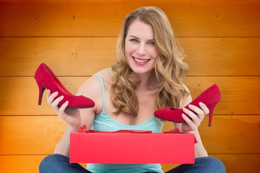 Woman holding pair of shoes discovered into the box against wooden planks background